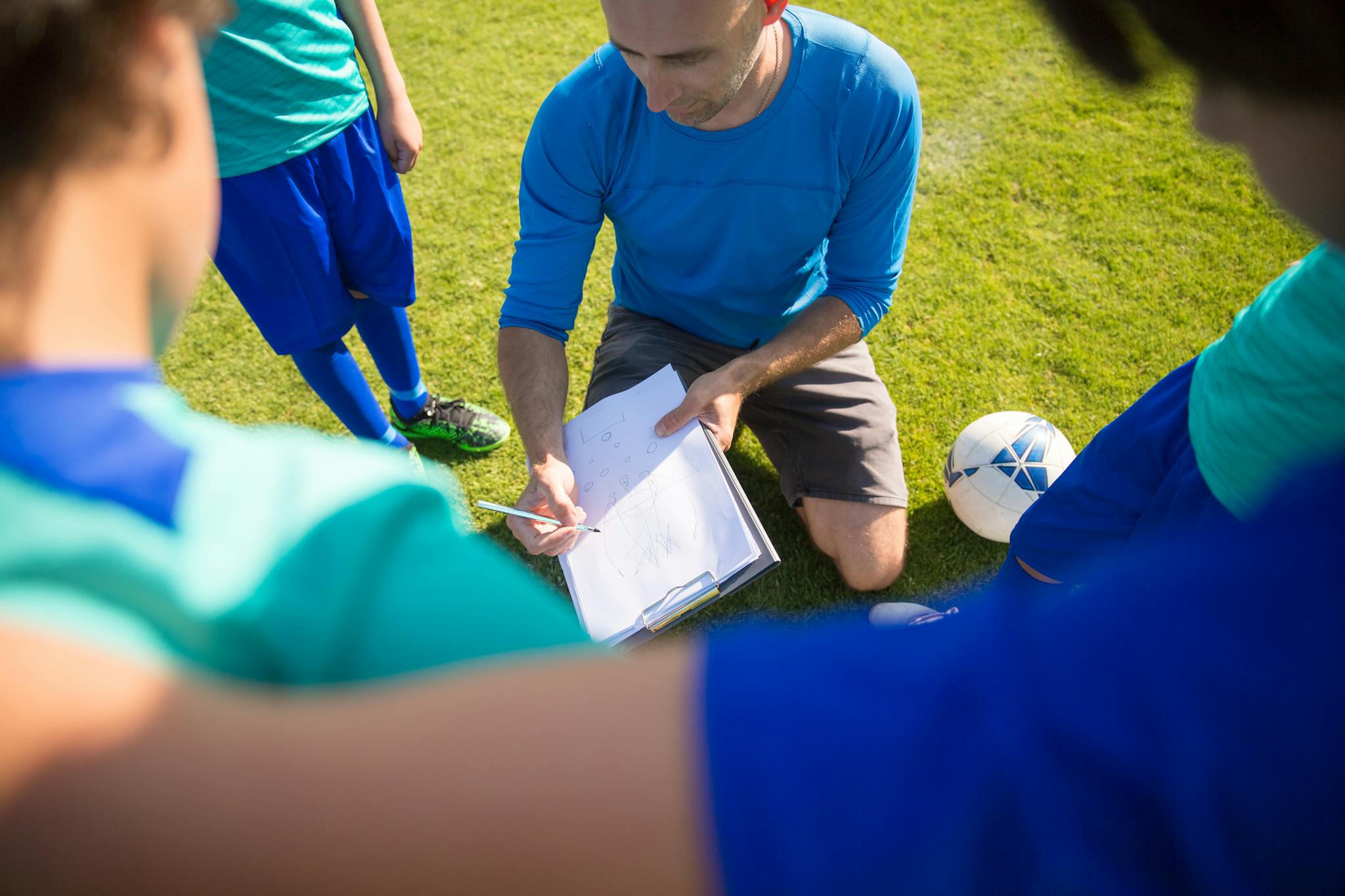 Coach instructing young soccer players during a practice session in Portugal.